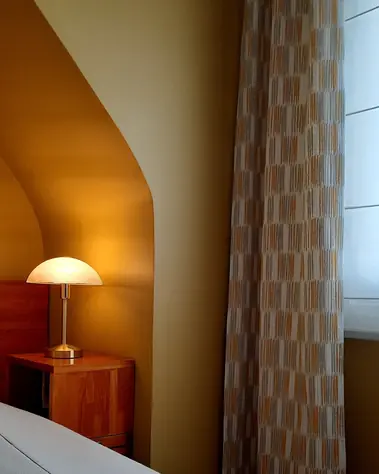 Mur peint teinte ocre et rideau sur-mesure à motifs géométriques dans une chambre