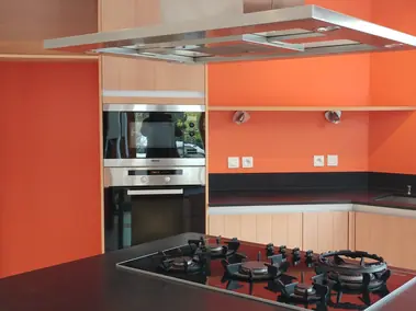 Peinture murale cuisine en orange vif avec finition lisse et bandeau noir en dessous