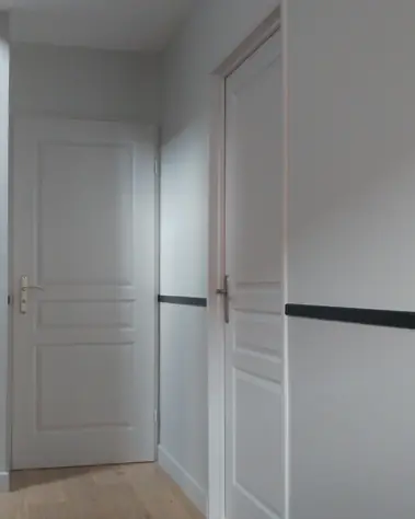 Peinture blanche sur murs et portes de couloir avec barre d'appui noire et parquet.
