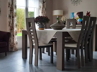 Rideaux sur-mesure à motifs végétaux et stores enroulables dans une salle à manger.