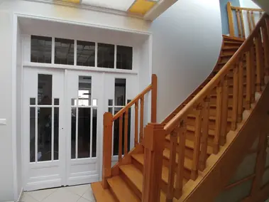 Peinture blanche sur murs et portes vitrées d'entrée, escalier en bois clair.