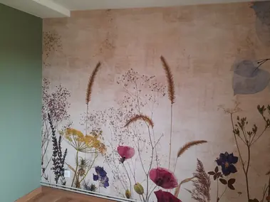 Pose de papier peint panoramique floral aux fleurs séchées sur fond beige et mur vert.