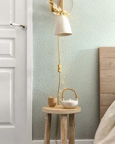 Pose de papier peint bleu pâle à motifs discrets dans une chambre avec porte blanche.