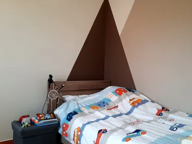 Peinture murale géométrique marron et beige clair dans une chambre d'enfant.