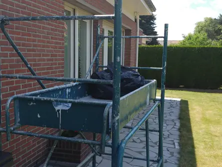 Échafaudage métallique posé contre une façade en brique pour travaux de peinture extérieure
