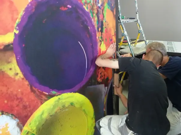 Pose d'un papier peint panoramique aux couleurs vives par des peintres décorateurs.