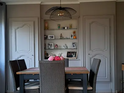 Salle à manger avec portes à panneaux peintes et moulures de plafond blanches.